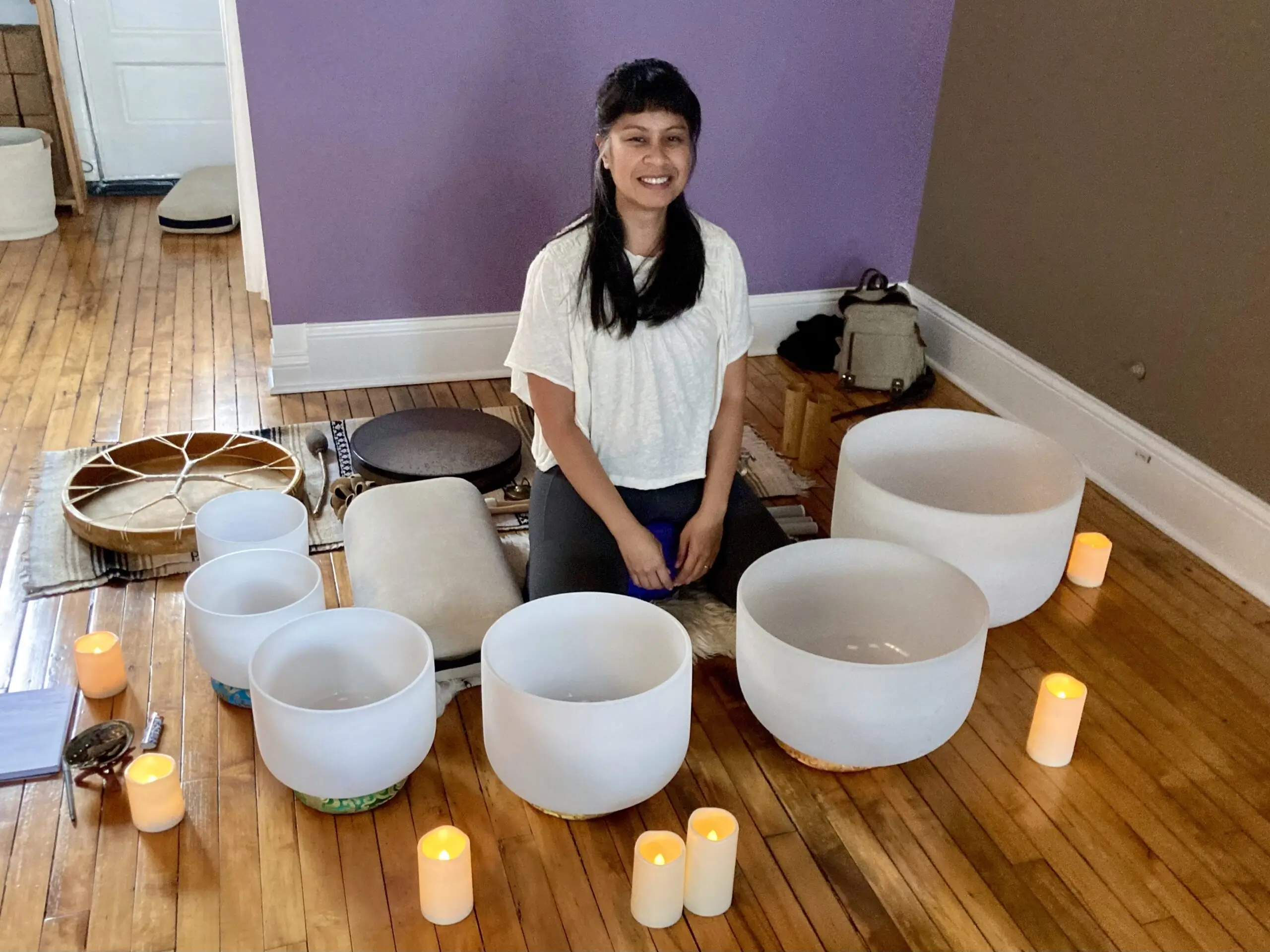 Person sitting with singing bowls and candles.